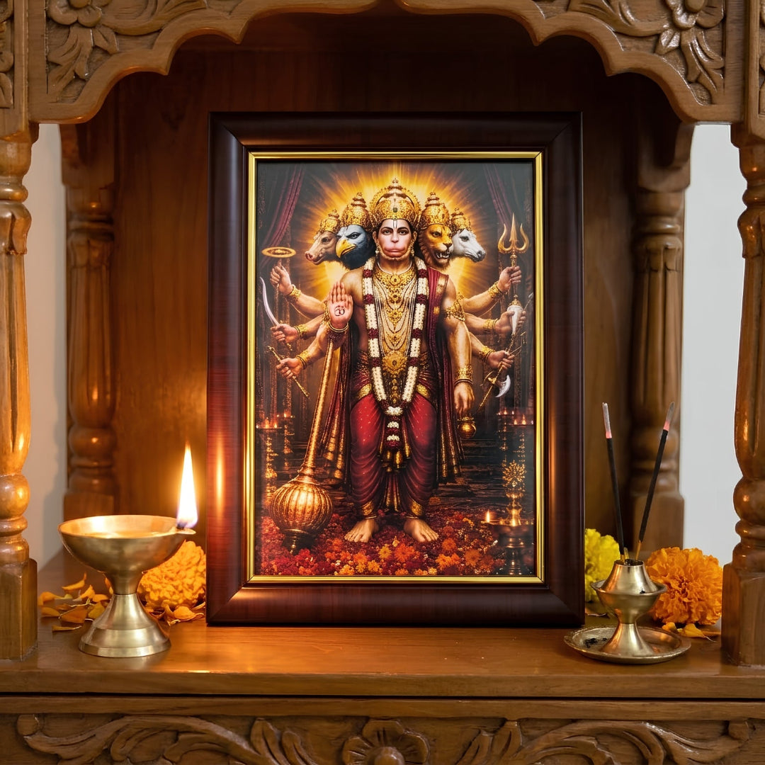 Panchmukhi Hanuman Ji Vastu protection frame placed inside a wooden home mandir, decorated with a glowing brass diya, incense sticks, and marigold flowers.